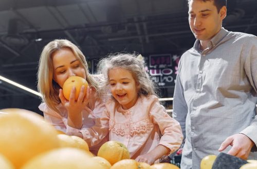 Family enjoying a cheerful shopping trip together at the grocery store, selecting fresh oranges.